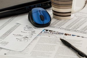 laptop with mouse and mug on documents - ЗАБЛОКУВАЛИ ПОДАТКОВУ НАКЛАДНУ: ЩО РОБИТИ?